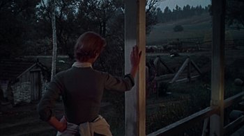 Movie still from “Friendly Persuasion” (1956), directed by William Wyler – A woman standing on a porch looking out a window; Medium shot, Low angle