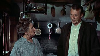 Movie still from “Friendly Persuasion” (1956), directed by William Wyler – An older man and a woman in a kitchen talking; Medium shot, Over the shoulder angle