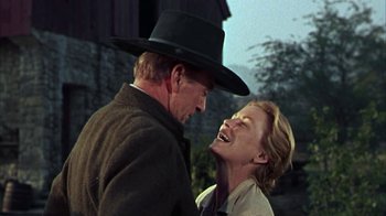 Movie still from “Friendly Persuasion” (1956), directed by William Wyler – A man and a woman smiling at each other in front of a barn; Medium shot, Low angle