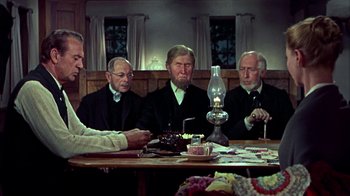Movie still from “Friendly Persuasion” (1956), directed by William Wyler – A group of men sitting around a table with a cake on it; Medium shot, High angle