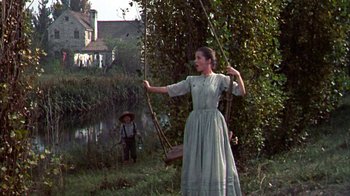 Movie still from “Friendly Persuasion” (1956), directed by William Wyler – A woman swinging on a rope swing in a field; Wide shot, Low angle