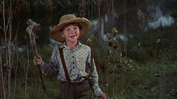 Movie still from “Friendly Persuasion” (1956), directed by William Wyler – A young boy wearing a straw hat while holding a stick; Medium shot, Low angle