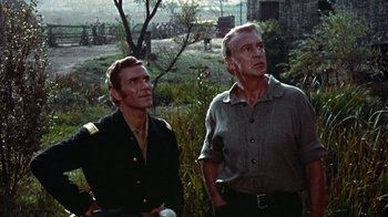 Movie still from “Friendly Persuasion” (1956), directed by William Wyler – Two men standing next to each other near a tree; Medium shot, Low angle