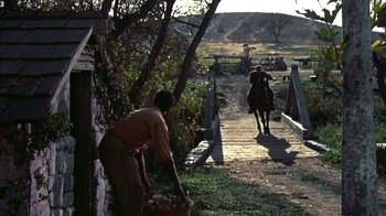 Movie still from “Friendly Persuasion” (1956), directed by William Wyler – A man on a horse and a woman on a horse on a bridge; Wide shot, Over the shoulder angle