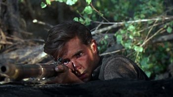 Movie still from “Friendly Persuasion” (1956), directed by William Wyler – A man is aiming a rifle in the woods; Close Up shot, Over the shoulder angle