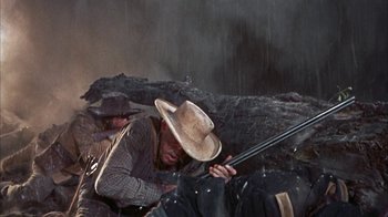 Movie still from “Friendly Persuasion” (1956), directed by William Wyler – A man in a cowboy hat is holding a rifle; Medium shot, Low angle
