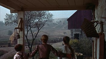 Movie still from “Friendly Persuasion” (1956), directed by William Wyler – Two people standing on a porch looking out at a barn; Wide shot, Low angle