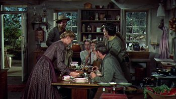 Movie still from “Friendly Persuasion” (1956), directed by William Wyler – A group of people sitting around a table; Wide shot, High angle