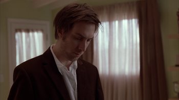 Movie still from “Friends with Money” (2006), directed by Nicole Holofcener – A man in a brown suit standing in front of a window; Close Up shot, Low angle