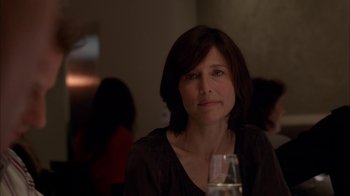 Movie still from “Friends with Money” (2006), directed by Nicole Holofcener – A person sitting at a table with a wine glass; Close Up shot, Over the shoulder angle