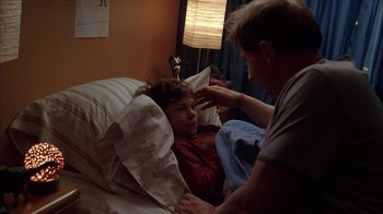 Movie still from “Friends with Money” (2006), directed by Nicole Holofcener – A man touching the forehead of a boy in a bed; Medium shot, Over the shoulder angle