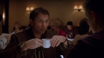 Movie still from “Friends with Money” (2006), directed by Nicole Holofcener – A man sitting at a table holding a coffee cup; Medium shot, Over the shoulder angle