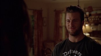 Movie still from “Friends with Money” (2006), directed by Nicole Holofcener – A young man smiling for the camera in a living room; Close Up shot, Over the shoulder angle