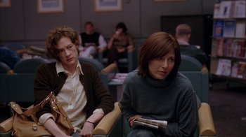 Movie still from “Friends with Money” (2006), directed by Nicole Holofcener – Two people sitting in a room with people in the background; Medium shot, Over the shoulder angle