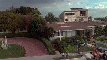 Movie still from “Friends with Money” (2006), directed by Nicole Holofcener – A man standing on the side of a road next to a house; Extreme Wide shot, High angle
