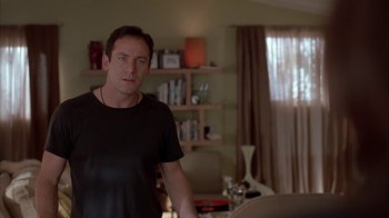 Movie still from “Friends with Money” (2006), directed by Nicole Holofcener – A man standing in a living room next to a bookshelf; Medium shot, Over the shoulder angle