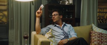 Movie still from “From Paris with Love” (2010), directed by Pierre Morel – A man sitting in a chair holding a piece of paper in his hand; Medium shot, Low angle