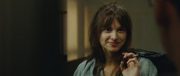 Movie still from “From Paris with Love” (2010), directed by Pierre Morel – A woman smiles while talking on a cell phone; Close Up shot, Over the shoulder angle
