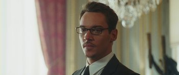Movie still from “From Paris with Love” (2010), directed by Pierre Morel – A man in a suit and tie wearing glasses; Close Up shot, Over the shoulder angle