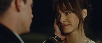 Movie still from “From Paris with Love” (2010), directed by Pierre Morel – A person with a hand on their ear; Close Up shot, Over the shoulder angle