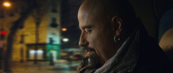Movie still from “From Paris with Love” (2010), directed by Pierre Morel – A man with a bald head looking into the distance; Close Up shot, Over the shoulder angle