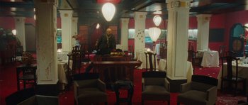 Movie still from “From Paris with Love” (2010), directed by Pierre Morel – A man sitting at a table in a restaurant; Wide shot, High angle