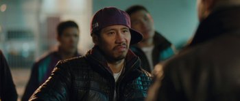 Movie still from “From Paris with Love” (2010), directed by Pierre Morel – A man wearing a purple hat and a leather jacket; Close Up shot, Over the shoulder angle