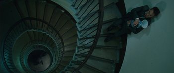 Movie still from “From Paris with Love” (2010), directed by Pierre Morel – A very pretty spiral stair case in a dark room; Wide shot, Overhead angle
