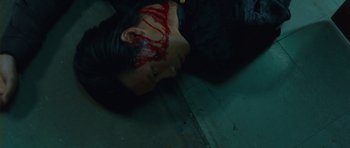 Movie still from “From Paris with Love” (2010), directed by Pierre Morel – A person with blood all over their face and head; Close Up shot, Overhead angle