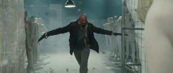 Movie still from “From Paris with Love” (2010), directed by Pierre Morel – A bald man is walking through a hallway; Wide shot, Low angle