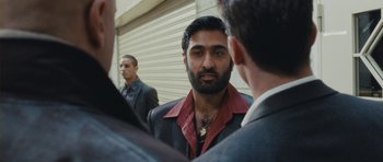 Movie still from “From Paris with Love” (2010), directed by Pierre Morel – A man with a beard is talking to two other men; Close Up shot, Over the shoulder angle