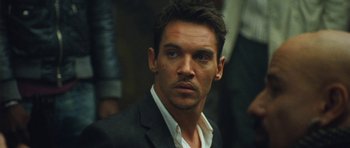 Movie still from “From Paris with Love” (2010), directed by Pierre Morel – A person wearing a suit and tie; Close Up shot, Over the shoulder angle