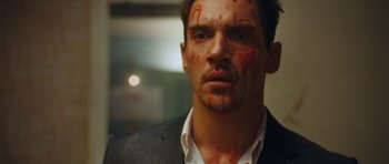 Movie still from “From Paris with Love” (2010), directed by Pierre Morel – A person with blood on his face; Close Up shot, Over the shoulder angle