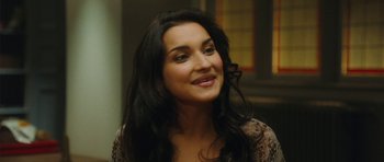 Movie still from “From Paris with Love” (2010), directed by Pierre Morel – A woman with long black curly hair smiling; Close Up shot, Over the shoulder angle