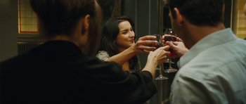 Movie still from “From Paris with Love” (2010), directed by Pierre Morel – A group of people that are holding wine glasses; Medium shot, Over the shoulder angle