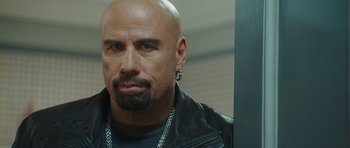 Movie still from “From Paris with Love” (2010), directed by Pierre Morel – A bald man with a beard wearing a leather jacket; Close Up shot, Over the shoulder angle