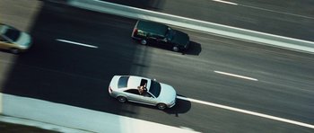 Movie still from “From Paris with Love” (2010), directed by Pierre Morel – Two cars driving down a highway on a sunny day; Extreme Wide shot, Overhead angle