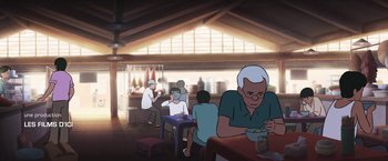 Movie still from “Funan” (2018), directed by Denis Do – An old man sitting at a table in front of a bowl of soup; Wide shot, Over the shoulder angle