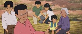 Movie still from “Funan” (2018), directed by Denis Do – An illustration of a family sitting on the ground; Medium shot, High angle
