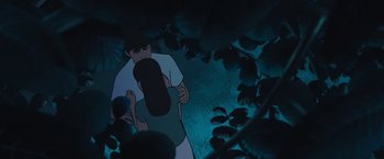 Movie still from “Funan” (2018), directed by Denis Do – A man holding a skateboard in front of some bushes; Medium shot, Low angle