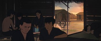 Movie still from “Funan” (2018), directed by Denis Do – A man sitting in front of another man in front of a building; Medium shot, Over the shoulder angle