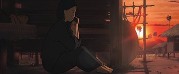 Movie still from “Funan” (2018), directed by Denis Do – A woman sitting on the ground with her hands in her mouth; Medium shot, Low angle