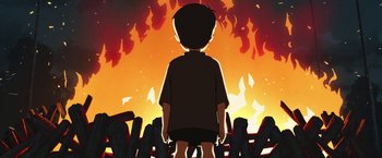 Movie still from “Funan” (2018), directed by Denis Do – A boy is standing in front of a fire; Wide shot, Low angle