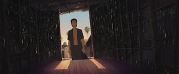 Movie still from “Funan” (2018), directed by Denis Do – A man standing in front of an open door; Wide shot, Low angle