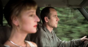Movie still from “Funny Games” (1997), directed by Michael Haneke – A man and a woman in a car driving; Close Up shot, Low angle