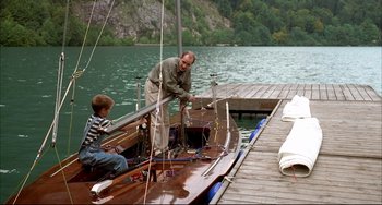 Movie still from “Funny Games” (1997), directed by Michael Haneke – A man and a boy on a boat in the water; Wide shot, High angle
