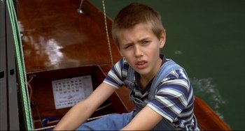 Movie still from “Funny Games” (1997), directed by Michael Haneke – A young boy sitting in front of a piano; Close Up shot, High angle