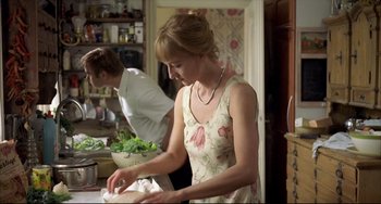 Movie still from “Funny Games” (1997), directed by Michael Haneke – A woman in a floral dress is cutting vegetables; Medium shot, Over the shoulder angle