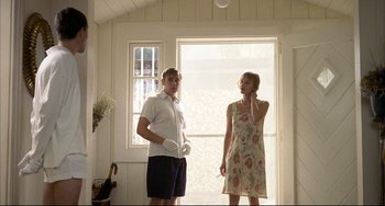 Movie still from “Funny Games” (1997), directed by Michael Haneke – A man and a woman standing next to each other in front of a window; Medium shot, Low angle