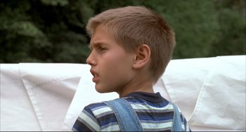 Movie still from “Funny Games” (1997), directed by Michael Haneke – A young boy is looking to the side; Close Up shot, Low angle